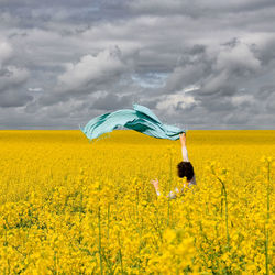 Woman holding scarf at oilseed rape field
