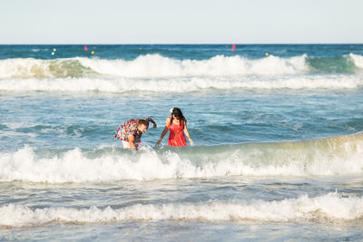 Rear view of women at beach against sky