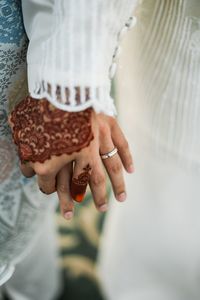 Midsection of couple holding hands during wedding ceremony