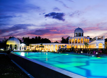 View of swimming pool at building against cloudy sky