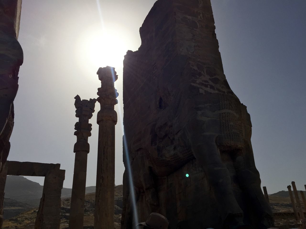 sun, sunbeam, low angle view, built structure, architecture, sunlight, lens flare, clear sky, sky, history, old ruin, building exterior, ancient, silhouette, sunny, famous place, travel destinations, architectural column, tourism, outdoors