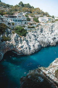 High angle view of rocks by sea against buildings