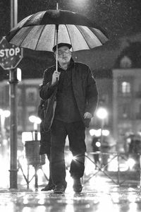 Full length portrait of man standing on wet rainy day