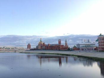 Buildings at waterfront against cloudy sky