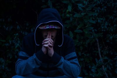 Worried man in hood clothing sitting at forest