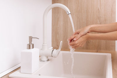 Cropped hand washing hands in sink