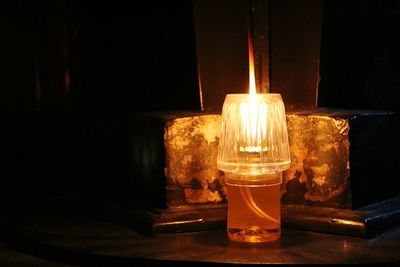 Close-up of lit tea light candles in darkroom