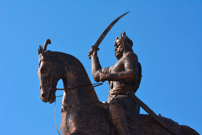 Low angle view of statue against clear blue sky