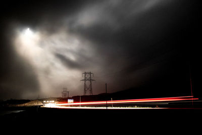 Light trails on road against sky at night