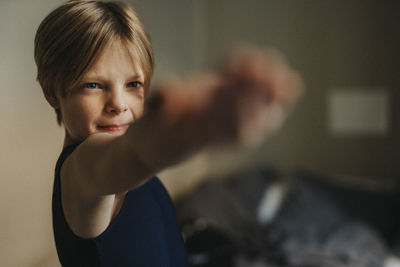 Dedicated boy with arms outstretched exercising at home