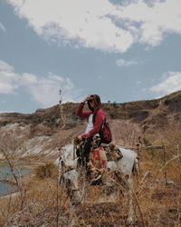 Portrait of woman sitting on land against sky