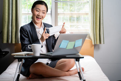 Young woman using mobile phone while sitting on table