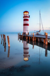 Lighthouse on pier over sea against clear sky
