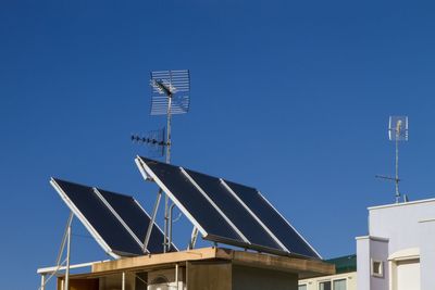 Low angle view of solar panels on house roof against clear blue sky