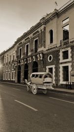 Cars on road by buildings against sky in city