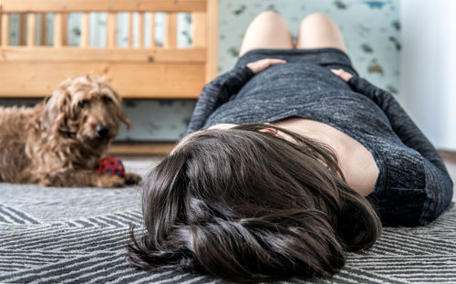 Low section of woman with dog resting on bed