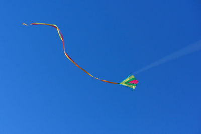 Low angle view of kite flying against clear blue sky