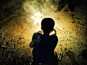 Rear view of silhouette boy standing at night