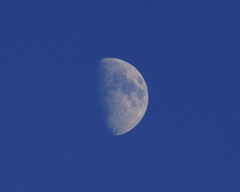 Low angle view of moon against clear blue sky