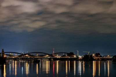 Illuminated bridge over river against sky at night