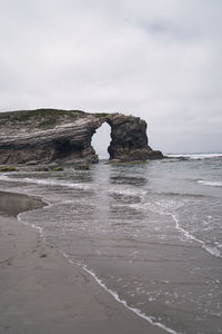 Rock formation on beach against sky