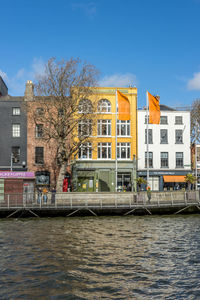 Canal by buildings against sky in city