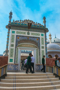 People at entrance of building against sky