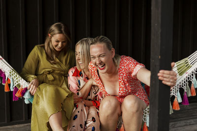 Smiling female friends sitting in hammock