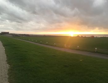 Scenic view of grassy field against sky during sunset