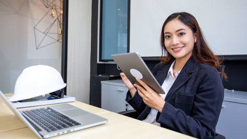 Portrait of young woman using laptop at office