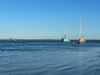 Sailboat sailing in sea against clear blue sky