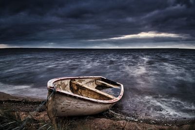 Abandoned boat on beach against sky