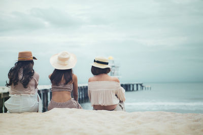 Rear view of people on beach against sky