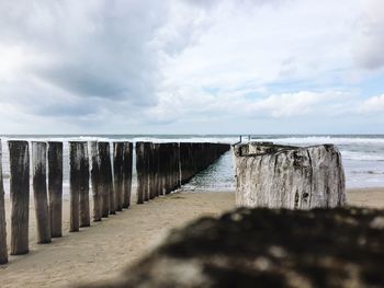 Wooden posts at beach against sky