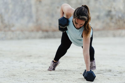 Young woman doing weight training in urban environment.