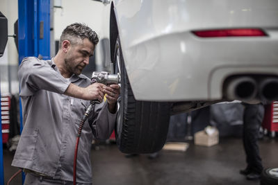 Car mechanic in a workshop changing tire