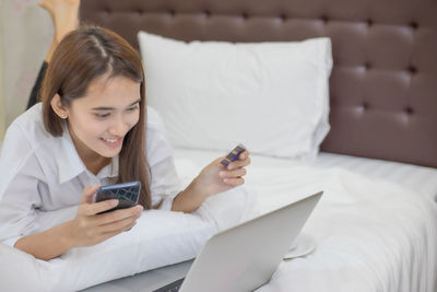 Young woman using mobile phone on bed