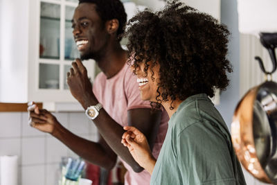 Side view of laughing friends looking away while standing at home