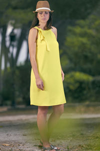 Full length of thoughtful woman standing against trees on field