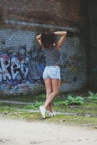 Rear view of woman standing against wall