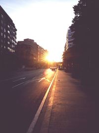 Road passing through city at sunset