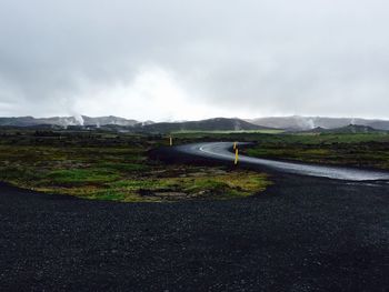 Country road against cloudy sky