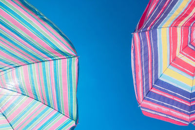 Low angle view of multi colored umbrellas against clear blue sky