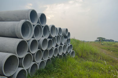 Stack of pipes on field against sky