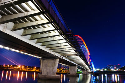 Low angle view of bridge over river against sky at night