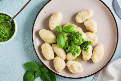 Potato gnocchi with pesto sauce on a plate on the table. italian traditional cuisine. top view. 