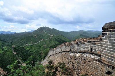 Scenic view of great wall on mountains against cloudy sky