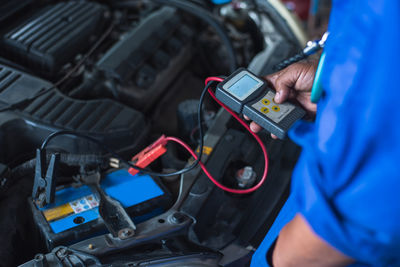 Midsection of man repairing car engine