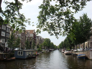 Boats moored in canal amidst buildings in city