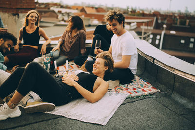 Happy friends relaxing on terrace during rooftop party